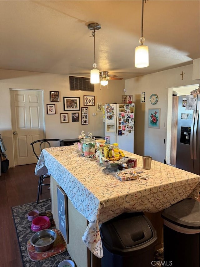 kitchen with pendant lighting, white refrigerator with ice dispenser, dark wood-type flooring, ceiling fan, and stainless steel fridge with ice dispenser