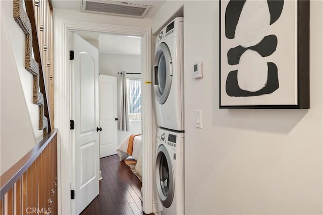 laundry area with dark wood-type flooring and stacked washer / drying machine