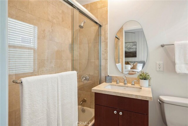 full bathroom featuring vanity, combined bath / shower with glass door, and toilet