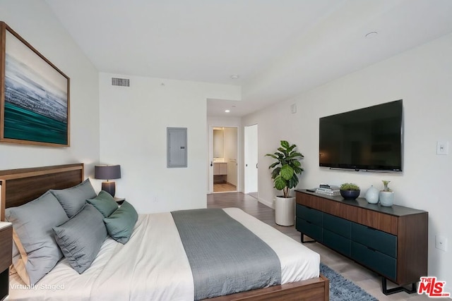 bedroom featuring connected bathroom, electric panel, and light wood-type flooring