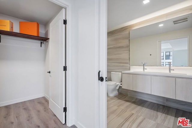 bathroom featuring vanity, wood-type flooring, tile walls, and toilet