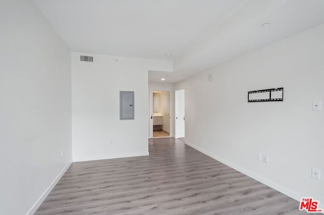 empty room with electric panel and light hardwood / wood-style flooring