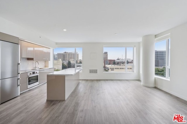 kitchen featuring a wealth of natural light, a kitchen island, stainless steel appliances, and light wood-type flooring