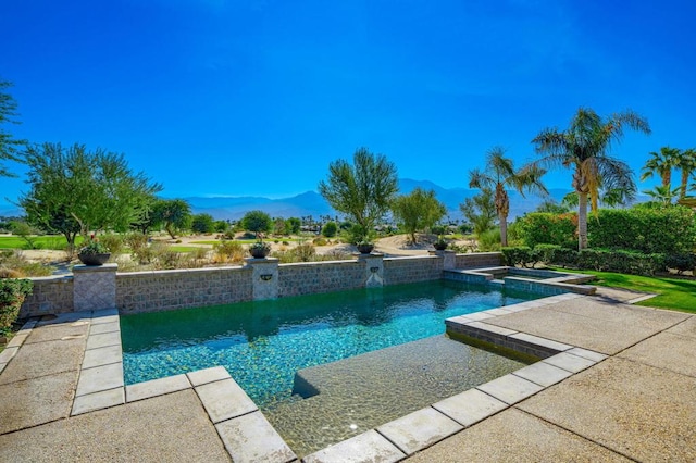 view of swimming pool featuring pool water feature, a mountain view, and an in ground hot tub