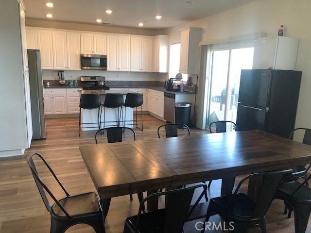 kitchen with stainless steel appliances, light wood-type flooring, a kitchen island, and white cabinets