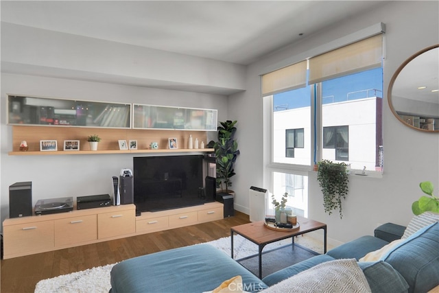 living room with a wealth of natural light and dark wood-type flooring