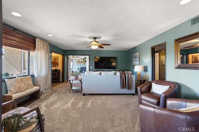 living room with a textured ceiling, ceiling fan, and light carpet