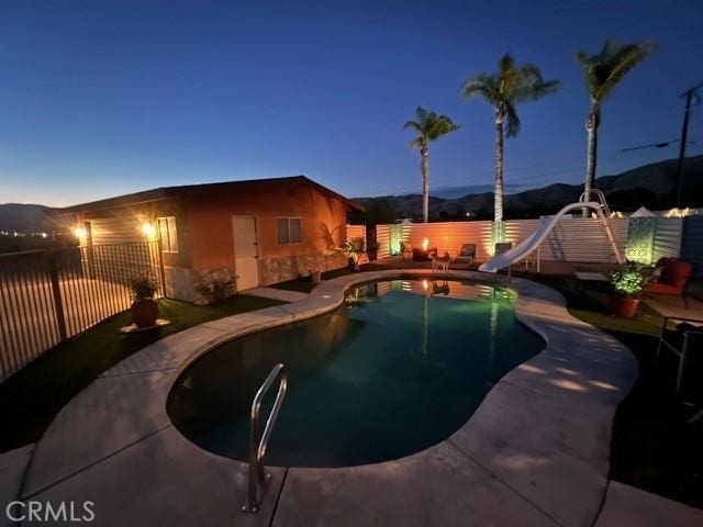 pool at dusk with a water slide and a mountain view