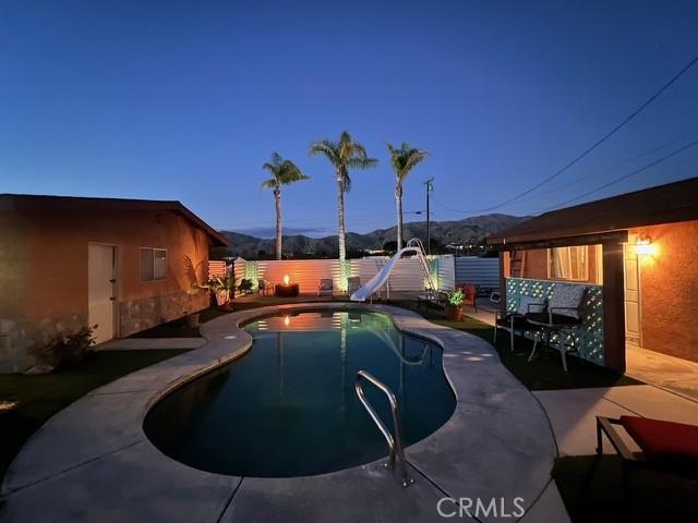 view of pool with a water slide, a patio area, and a mountain view