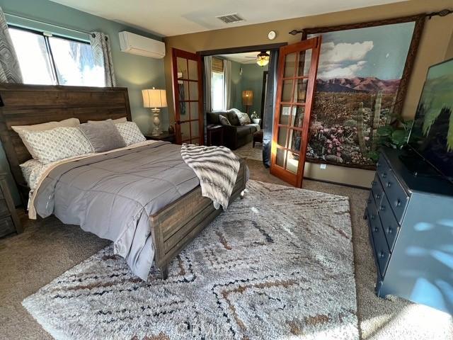 bedroom featuring french doors, carpet, and a wall mounted air conditioner