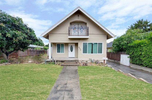 bungalow-style house with a balcony and a front lawn