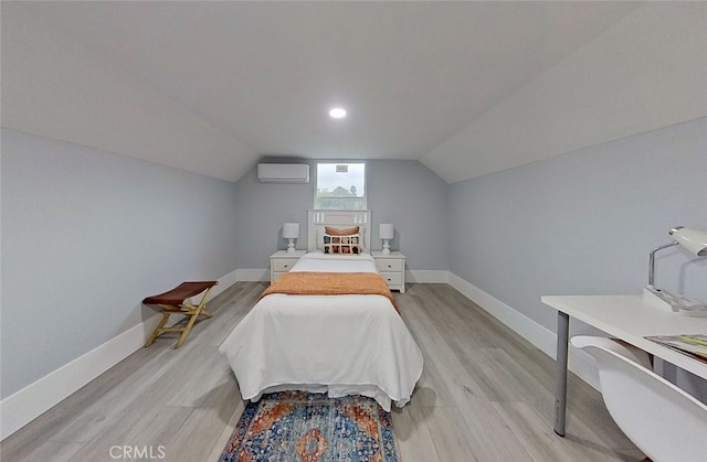 bedroom featuring light hardwood / wood-style floors, an AC wall unit, and lofted ceiling