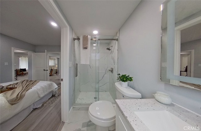 bathroom with a shower with door, vanity, and toilet