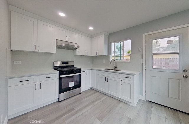 kitchen featuring stainless steel range, white cabinets, light hardwood / wood-style flooring, and sink