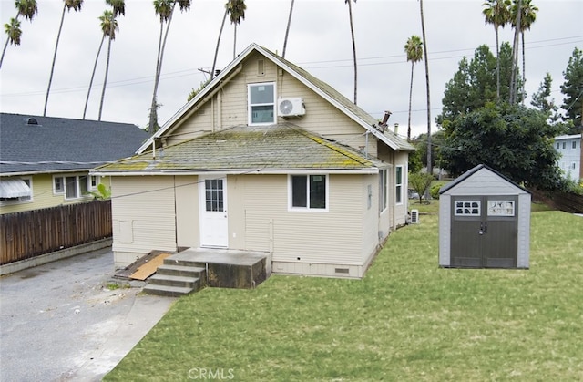 rear view of property with a shed and a lawn