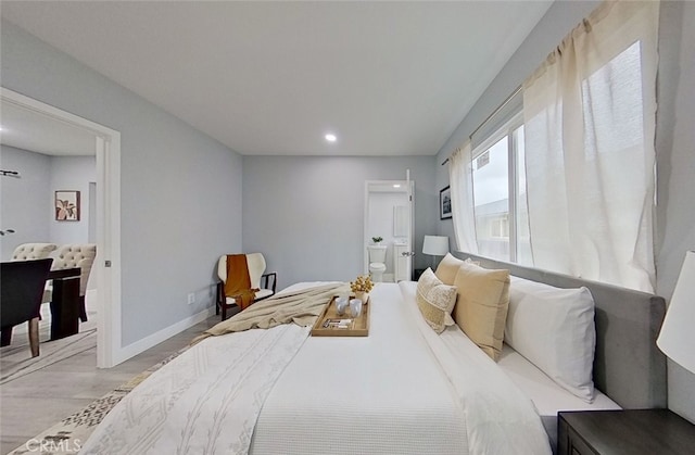 bedroom with ensuite bathroom and light tile patterned floors