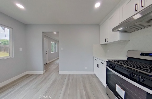 kitchen featuring a healthy amount of sunlight, light wood-type flooring, white cabinetry, and stainless steel gas range