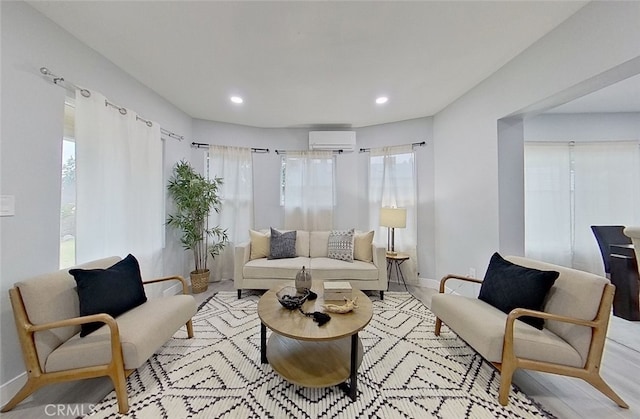 living room with a wall mounted air conditioner, light hardwood / wood-style floors, and a healthy amount of sunlight