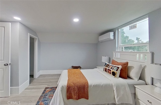 bedroom featuring a wall mounted air conditioner, vaulted ceiling, and light hardwood / wood-style flooring