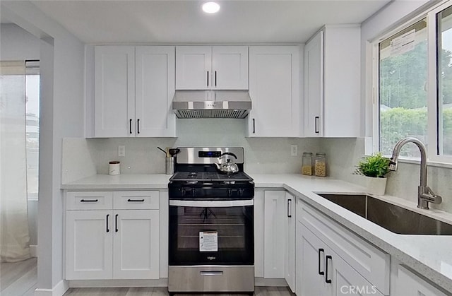 kitchen with sink, white cabinetry, stainless steel electric stove, and exhaust hood