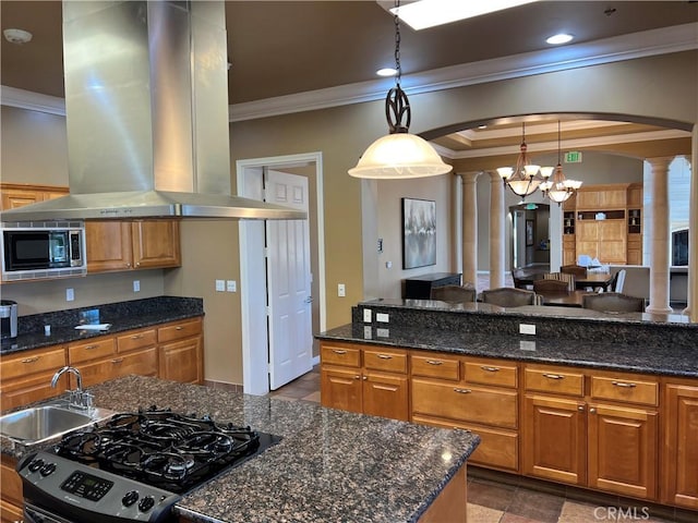 kitchen featuring island exhaust hood, black stove, ornate columns, hanging light fixtures, and stainless steel microwave