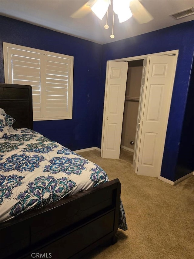 bedroom with ceiling fan, light colored carpet, and a closet