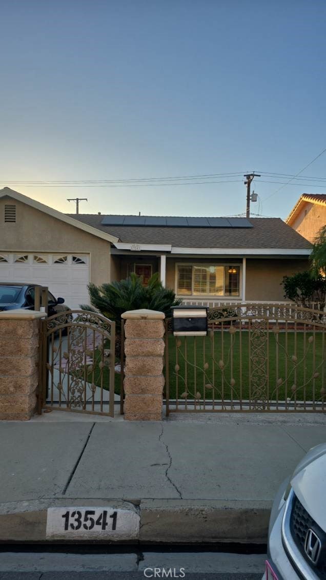 single story home featuring solar panels and a garage