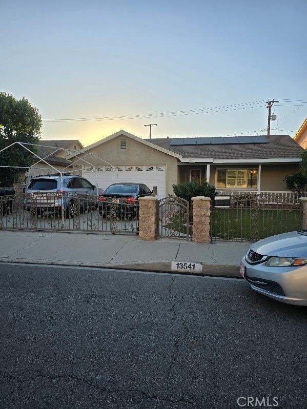 ranch-style house with solar panels and a garage