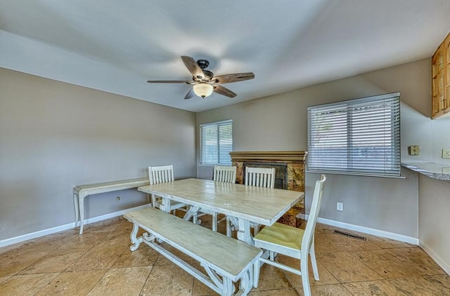 dining area with ceiling fan and a fireplace