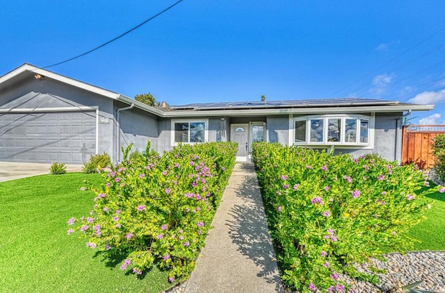 ranch-style home featuring a front lawn, a garage, and solar panels