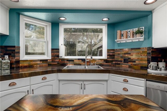 kitchen featuring decorative backsplash, white cabinetry, dishwasher, and sink