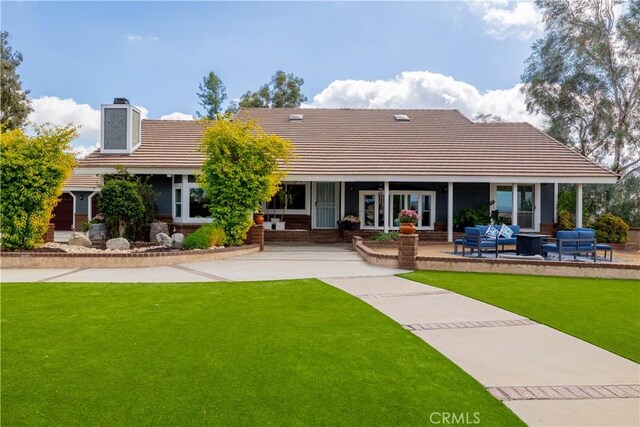 rear view of house with a yard, a patio, and outdoor lounge area