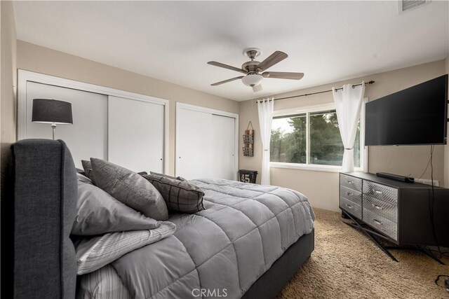 carpeted bedroom featuring two closets and ceiling fan