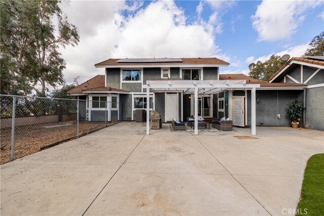 rear view of property with an outdoor hangout area, solar panels, a pergola, and a patio area