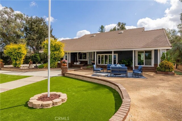 rear view of house with a lawn, outdoor lounge area, and a patio area