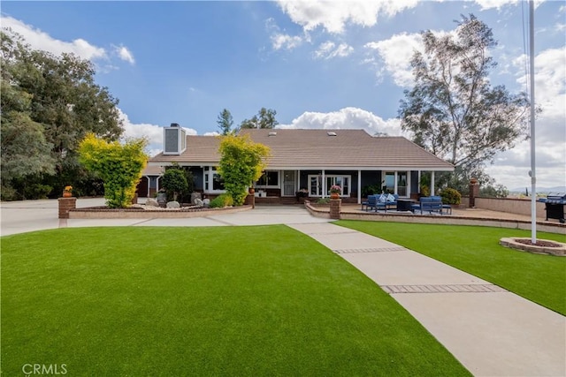 view of front of property with a tiled roof, a front yard, and a patio area