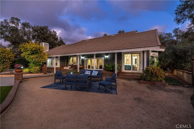 back house at dusk featuring an outdoor living space and a patio