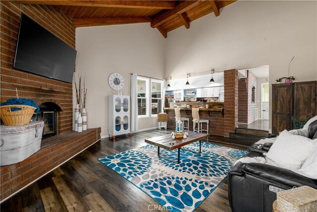 living room with a fireplace, beamed ceiling, dark hardwood / wood-style flooring, and plenty of natural light