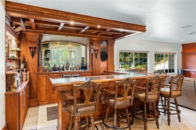 bar featuring beamed ceiling, light tile patterned flooring, and coffered ceiling