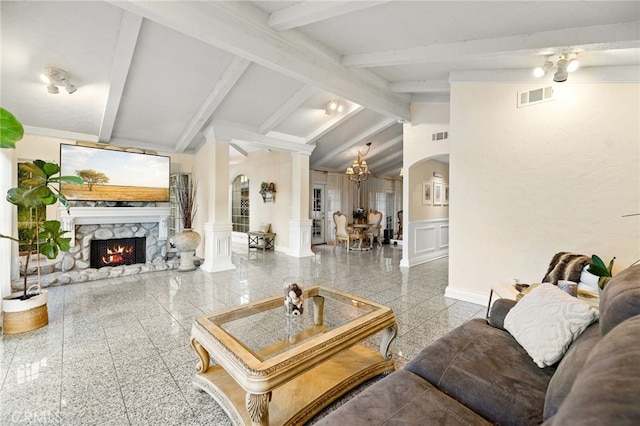 living room featuring lofted ceiling with beams, a fireplace, and decorative columns