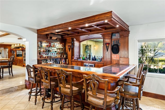 bar featuring beamed ceiling and light tile patterned floors