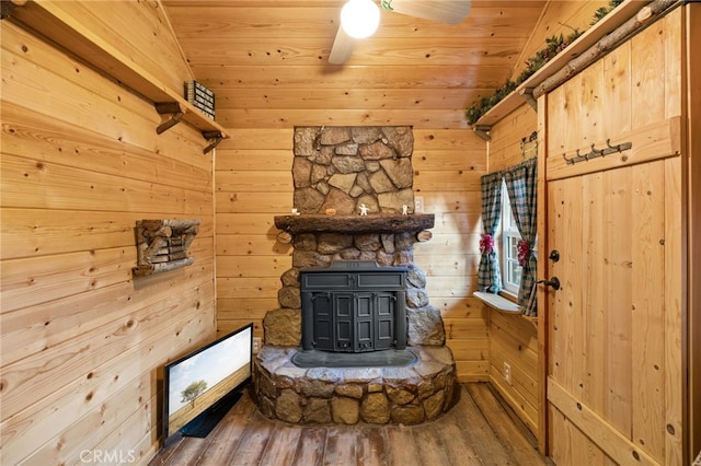 unfurnished living room featuring wood ceiling, wood walls, a wood stove, and hardwood / wood-style floors