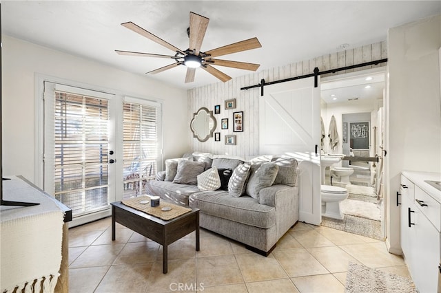 living room featuring ceiling fan, light tile patterned flooring, and a barn door