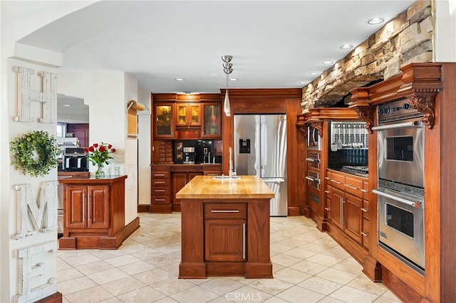 kitchen featuring appliances with stainless steel finishes, wood counters, a center island, and light tile patterned floors