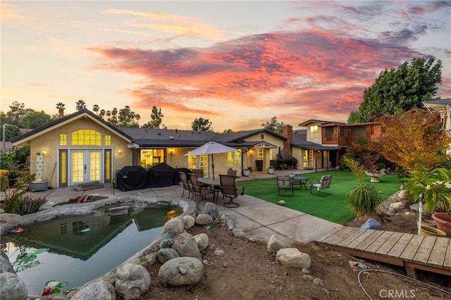 back house at dusk with a patio area and a yard