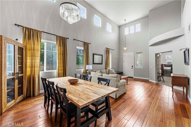 dining area featuring hardwood / wood-style floors, plenty of natural light, and a towering ceiling