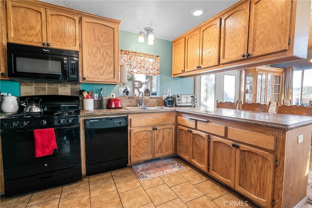 kitchen with kitchen peninsula, decorative backsplash, sink, and black appliances