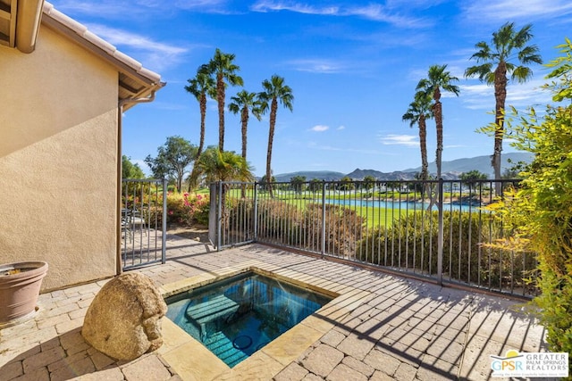 view of pool with an in ground hot tub, a patio, and a water and mountain view