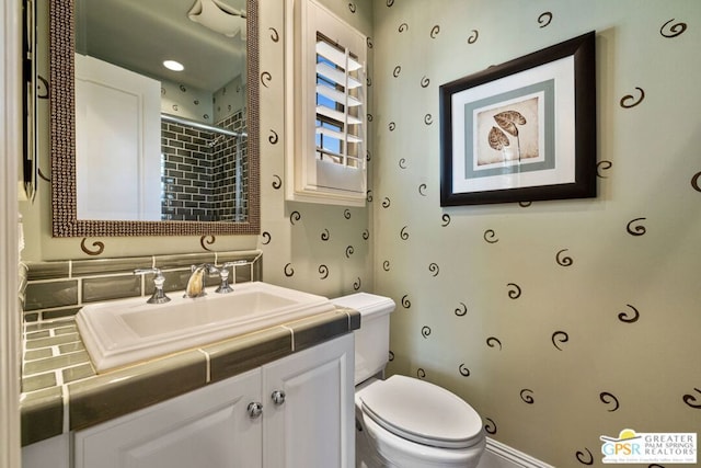 bathroom with walk in shower, vanity, and toilet