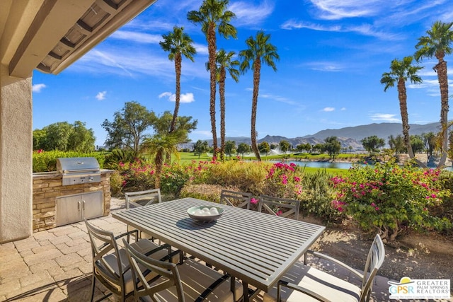 view of patio with a grill, a water and mountain view, and exterior kitchen